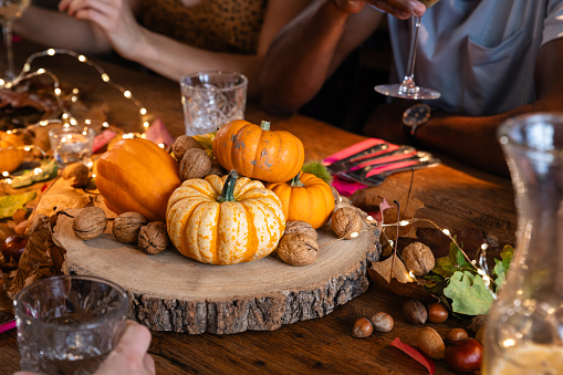 Close up view of an oak wood table decorated for a delightful thanksgiving evening, the table is adorned with twinkling fairy lights and rustic pumpkins in a restaurant in Newcastle, England.