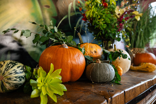 Close up of an oak wood table decorated for a delightful thanksgiving evening, the table is adorned with twinkling fairy lights and rustic pumpkins in a restaurant in Newcastle, England.