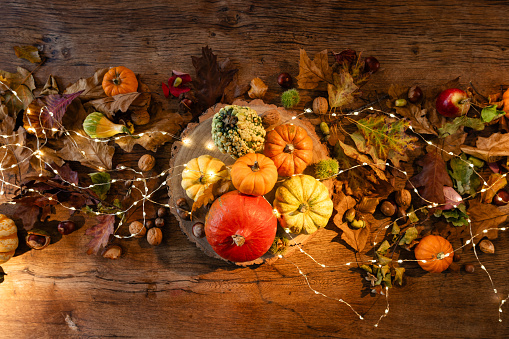 Directly above view of an oak wood table decorated for a delightful thanksgiving evening, the table is adorned with twinkling fairy lights and rustic pumpkins in a restaurant in Newcastle, England.