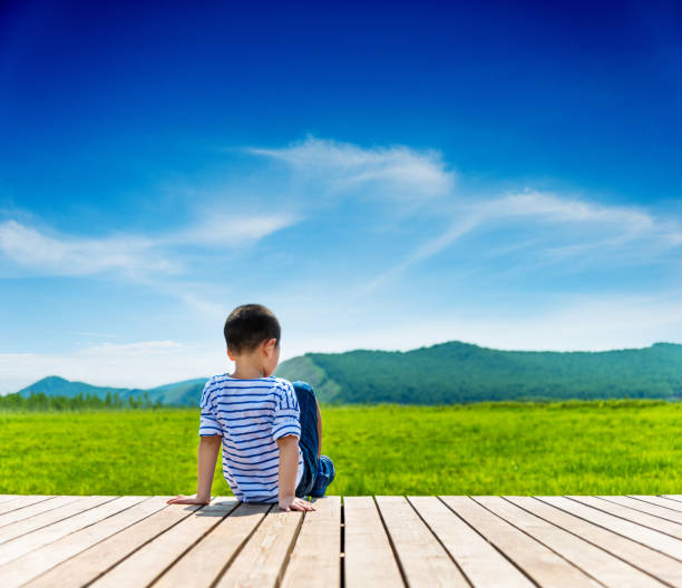 Little boy sitting on wooden sidewalk