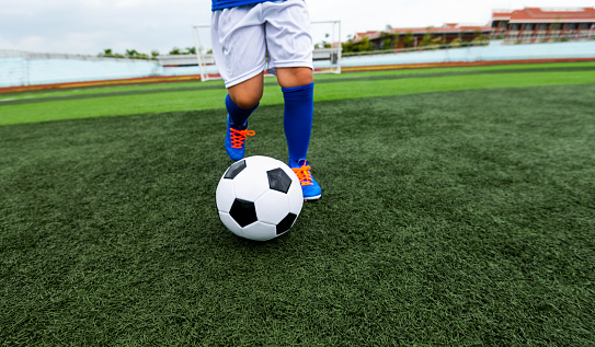 Low section of young boy feet kicking a soccer ball