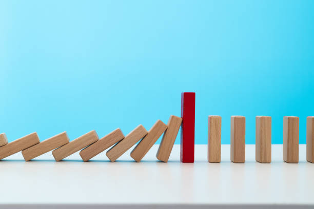 istock Red wooden block stop other falling dominos 1629632179