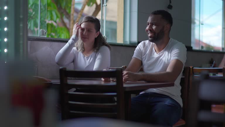 Candid Friends seated at cafeteria table in conversation. Diverse Brazilian people at restaurant meetup, lifestyle friendship