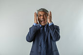 Frustrated senior male professional anger and gesturing while standing on white background