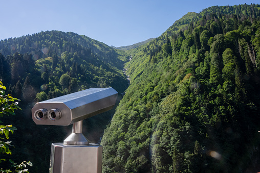 A viewing platform with binoculars on a background of mountains.