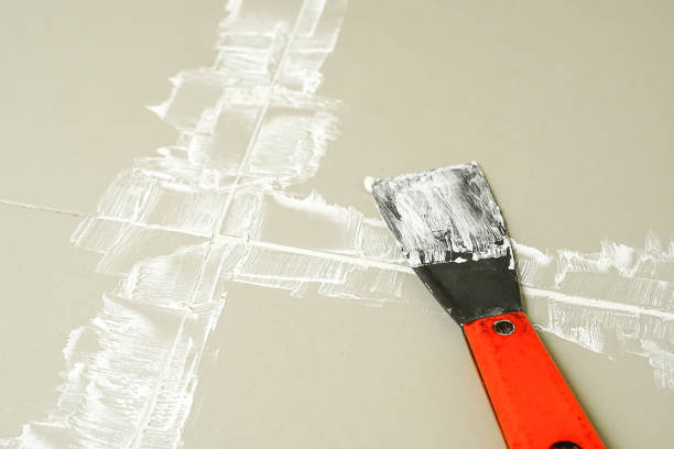 istock Grouting ceramic tiles. Tilers filling the space between tiles using a Stainless steel trowel. 1629678802