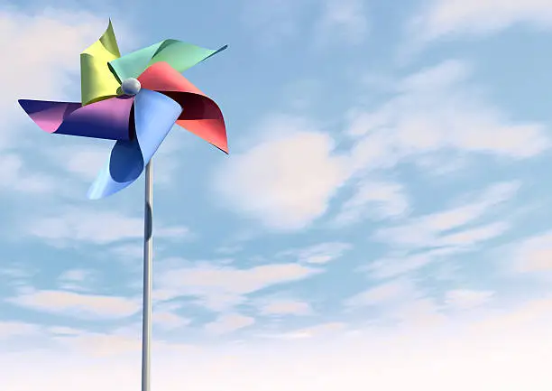 A regular toy pinwheel windmill with five differently colored vanes on a stick on a bluesky and cloud background