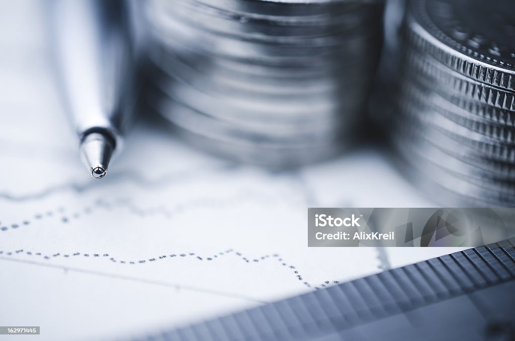 Financial Concept A pen and financial graph in shallow focus next to stacks of coins. Close-up Stock Photo