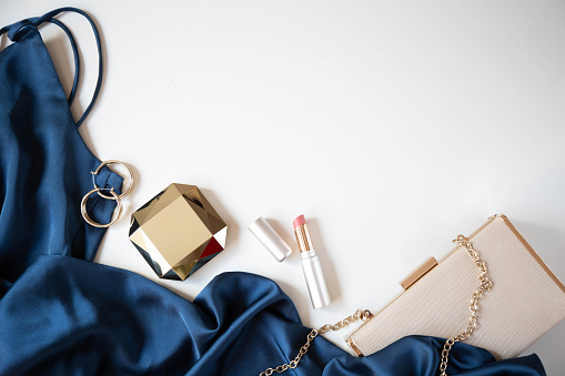 Women’s accessories, handbag and cocktail dress in blue are on a light background.