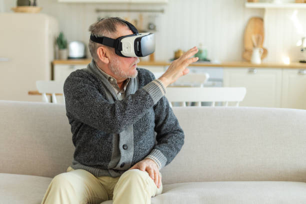 istock Excited mature senior man wearing using virtual reality metaverse VR glasses headset at home. Grandfather touching air during VR experience on virtual reality helmet. Simulation hi-tech videogame. 1629751526