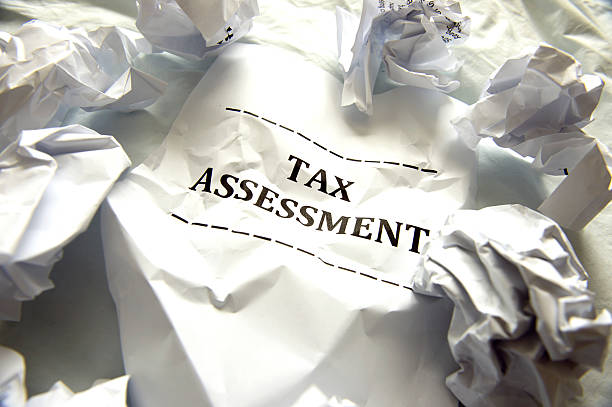 Income tax assessment notice sits with balled up crumpled papers stock photo