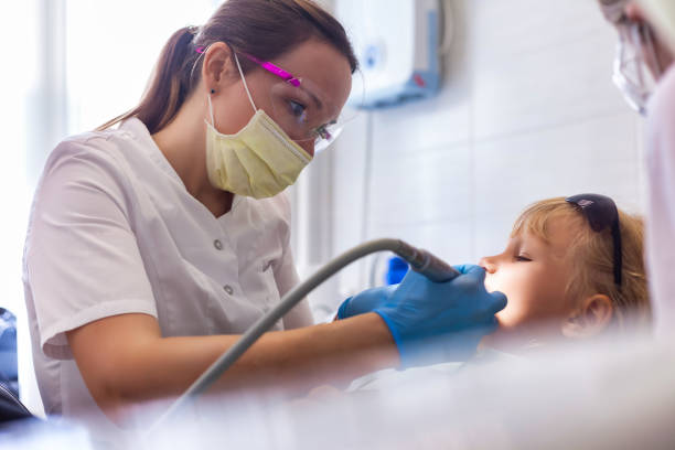 životní styl fotografie zubaře lékař dělá ošetření zubů holčička 5-6 let v zubní ordinaci na klinice. zubař s ošetřujícími zuby děvčátko. koncepce stomatologie pro děti. kopírování reklamního textového prostoru - bolest zubů fotky - stock snímky, obrázky a fotky