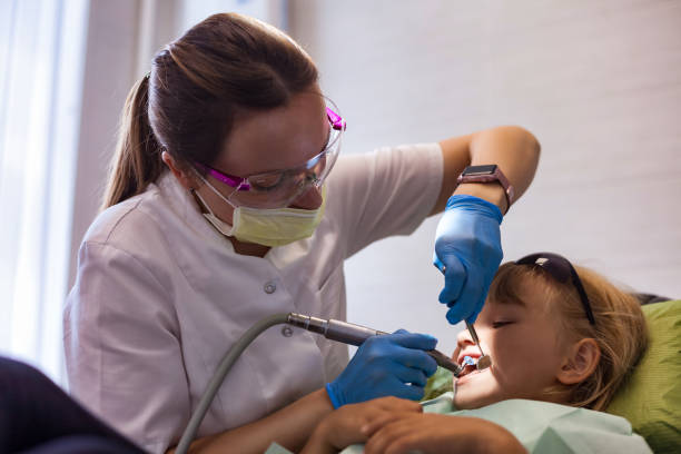 zubař lékař dělá ošetření zubů holčička 5-6 let stará v zubní ordinaci. realistická fotografie zubaře s ošetřujícími zuby dítě dívka na klinice. koncepce lékařské dětské stomatologie. kopírovat textový prostor - bolest zubů fotky - stock snímky, obrázky a fotky