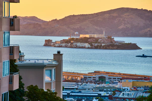 l’île d’alcatraz dans la baie de san francisco avec un ciel jaune au-dessus de nos têtes et un port en contrebas - san francisco county sunrise nobody sky photos et images de collection