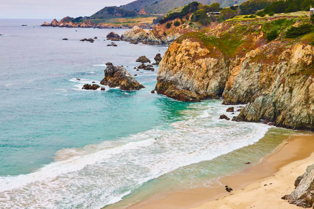 istock Beautiful ocean waves crashing against shoreline with yellow faced cliffs and crags 1629771095
