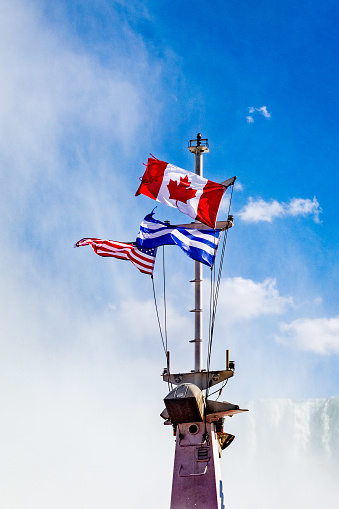 Niagara Falls, on the famous Falls boat tour, the Canadian and American flag flying on the mast of Niagara Cruise Boat.