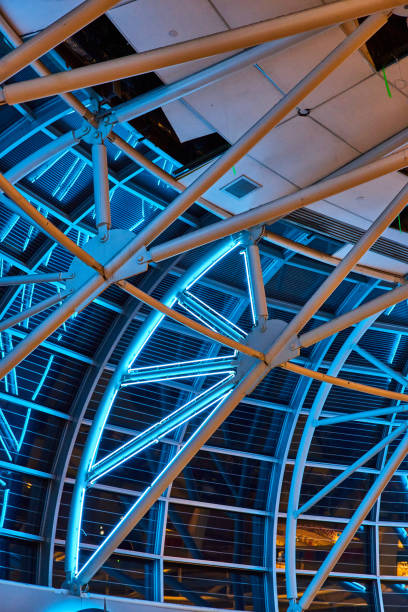 istock Curved wall of windows leading to ceiling with white beams illuminated by neon blue lights 1629781640