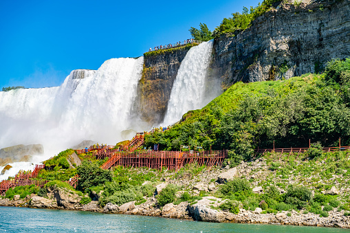 View on the Bridal Veil Falls and American Falls of the Niagara Falls, the part of Goat Island, the Cave of the Winds Lookout, stairs and platforms, wooden walkways, Niagara Falls, New York, USA. High quality photo.