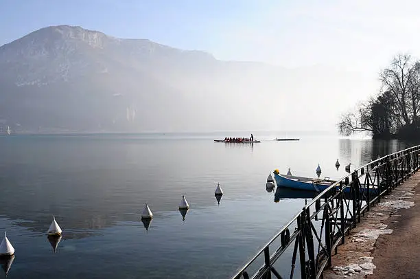 Dragon boat on  Annecy lake and mountains at morning on winter time, France