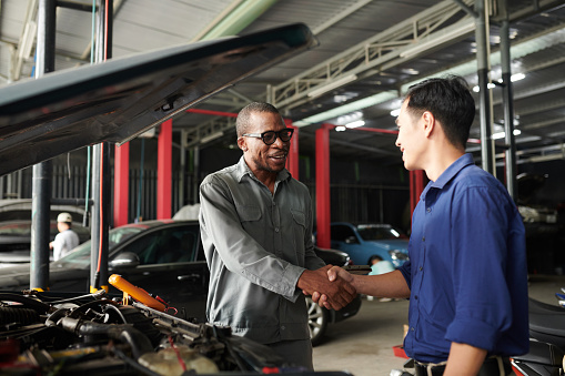 Positive mechanic shaking hand of owner of car that needs to be repaired