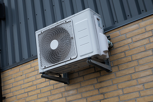 Heat Pump air condition mounted on yellow brick wall in industrial area