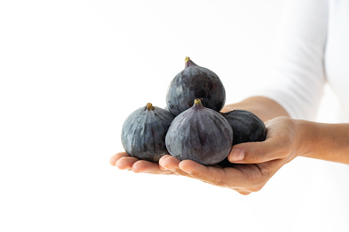 Woman holding figs, white background.