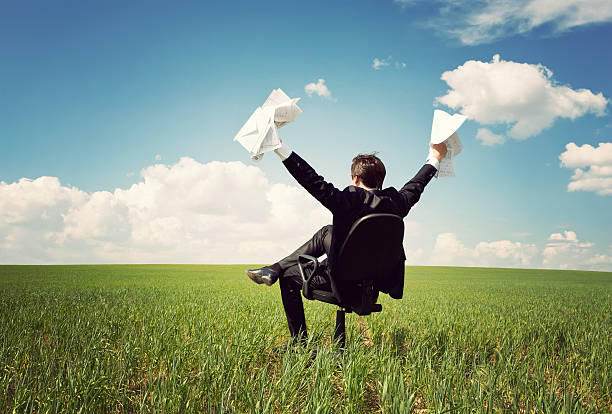 istock businessman sitting on a chair in field and holding documents 162988108
