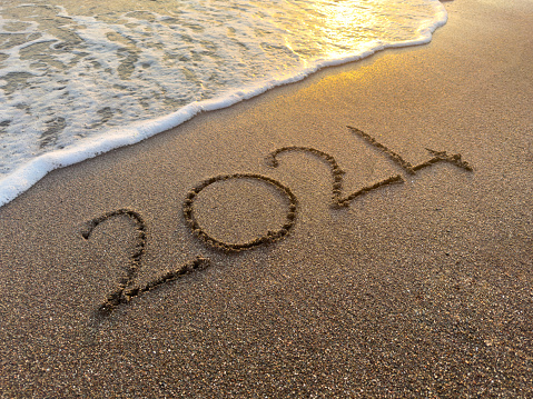 2024 new year. Numbers 2024 on the sand with sea wave in the beach