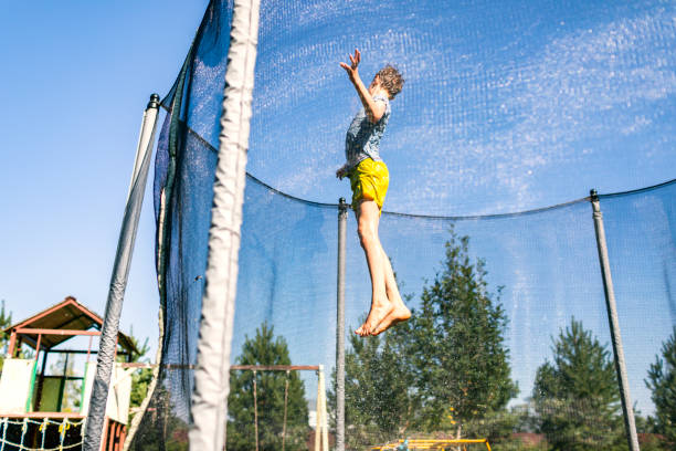 istock Boy jumping on trampoline at backyard with water sprayer 1629893442