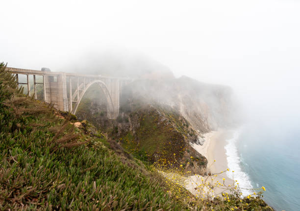 malerischer nebel, der über der brücke in big sur, kalifornien, am pacific coast highway, der bixby creek bridge und der rocky creek bridge aufsteigt - fog bridge california balance stock-fotos und bilder