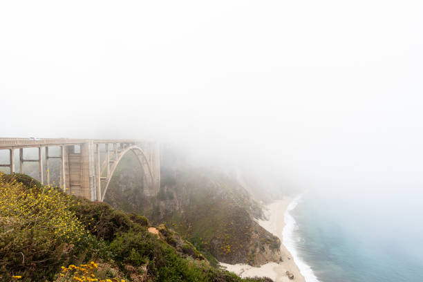 malerischer nebel, der über der brücke in big sur, kalifornien, am pacific coast highway, der bixby creek bridge und der rocky creek bridge aufsteigt - fog bridge california balance stock-fotos und bilder