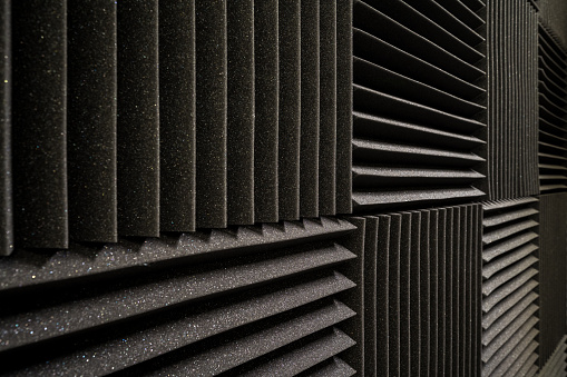 A pattern of black, square, soundproof foam blocks on a wall in an abstract background.