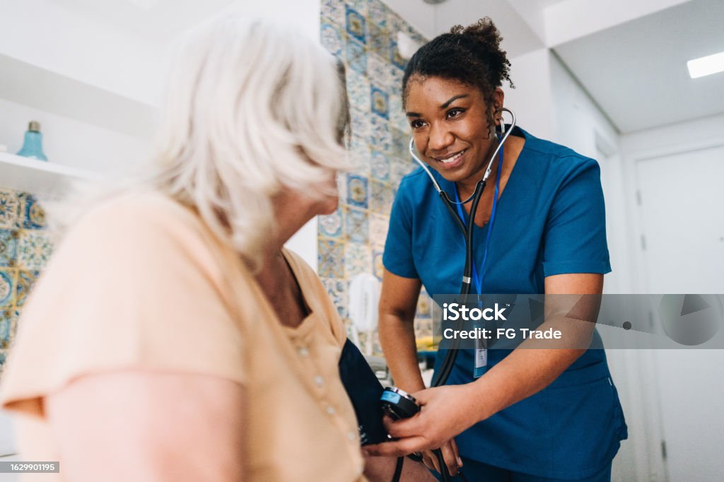 Nurse taking blood pressure of a senior woman at home Nurse Stock Photo Nurse taking blood pressure of a senior woman at home Nurse Stock Photo