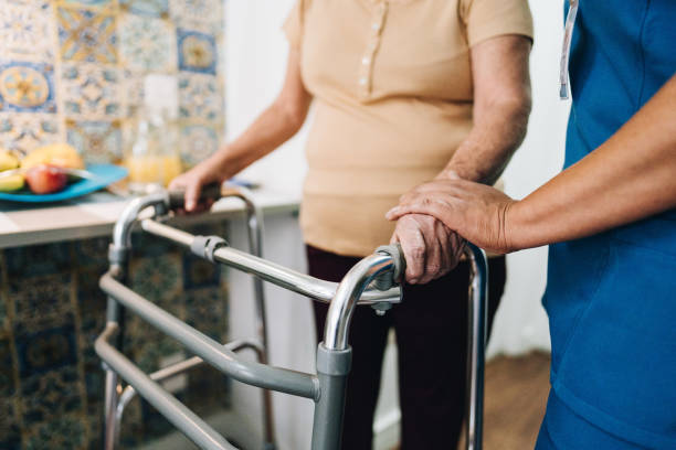 home caregiver helping a senior woman walking at home - ouderenzorg stockfoto's en -beelden