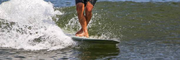 istock Man surfing with his legs crossed while walking up his board 1629904248