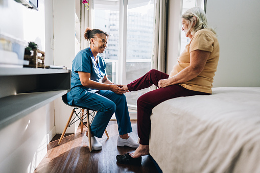 Nurse massaging a senior woman's foot at home