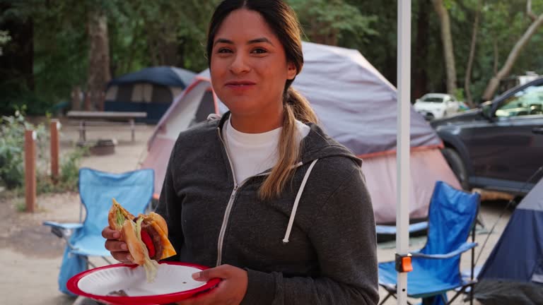 Woman Wearing Gray Hoodie Bites Into Cheeseburger