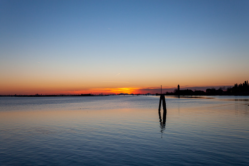 Burano, Italy - February 12, 2023: Sunset over the Venice lagoon seen from Burano island.
