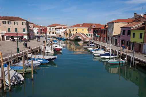 Murano, Italy - February 13, 2022: View of the canals of Murano on a sunny day, there are people.