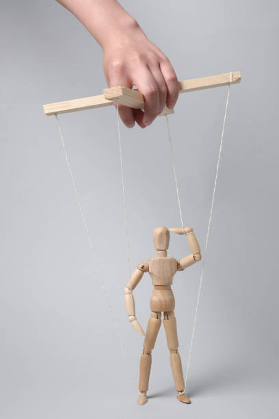 istock Woman pulling strings of puppet on light grey background, closeup 1629987393