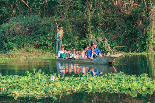 Chitwan, Nepal - March 31, 2014: people on a boat trip at the river in Chitwan national park in Nepal to watch animals like crocodiles, birds and fishes