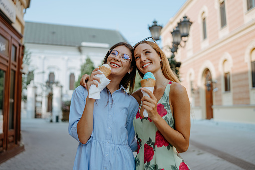 This image signifies friendship as two young women bond over ice cream in the city