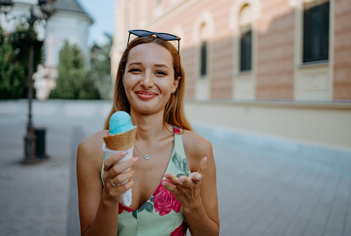 This image showcases a relaxed moment as a young woman enjoys an ice cream cone in the city