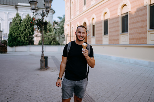 This image captures the joy of an urban treat as a young man enjoys ice cream on a vibrant city street