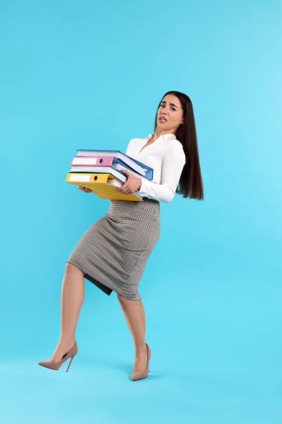 istock Stressful woman with folders walking on light blue background 1630042716