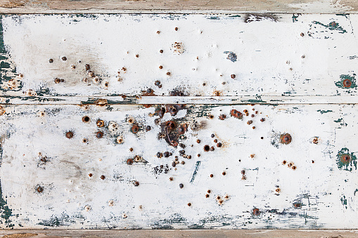 rusty and scratched white metal panel background with bullet holes