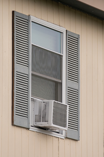 Vertical shot of an old window air conditioner in a low rent apartment window.