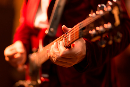 Guitar player fingers on guitar, available light, high iso shot, shallow depth of field