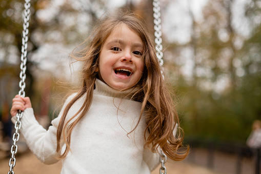 Happy child girl on swing, summer time. Life Events.  Retro toned, Soft focus effect