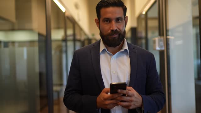 Portrait of a businessman holding a mobile phone at office